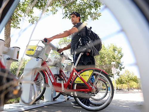 MSU Denver junior Aldo Ascencia holds on to a B-cycle bike that are available to rent at a station located on Auraria Campus. Photo  by Alyson McClaran