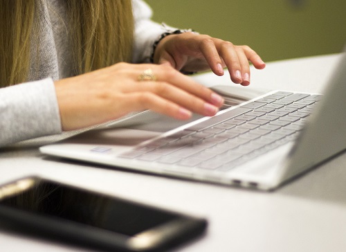 Hands typing on laptop