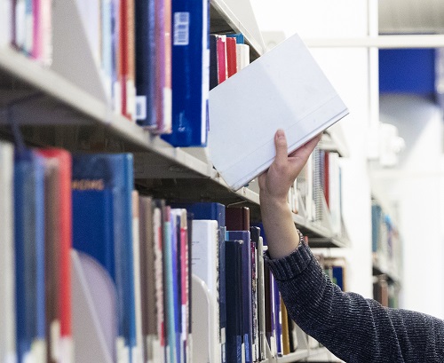 Hand grabbing book from shelf