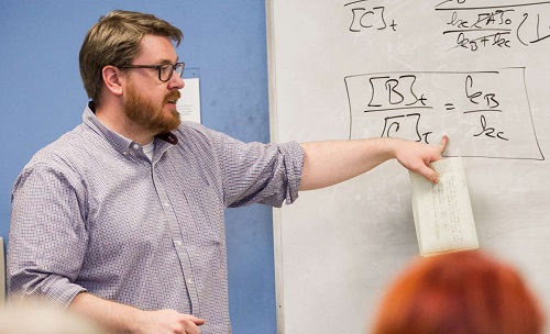 Teaching standing near white board in front of classroom