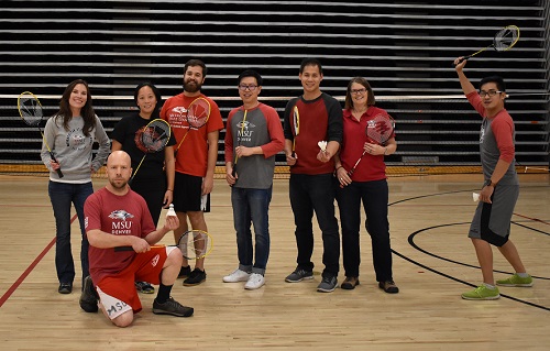 Colleagues posing with badminton raquets