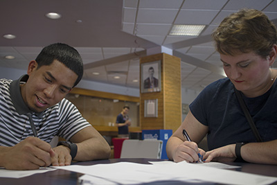 Two students writing letters to future Roadrunners at Transfer graduation party.