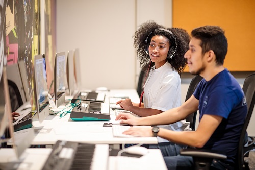 Two students working on desktop computers.