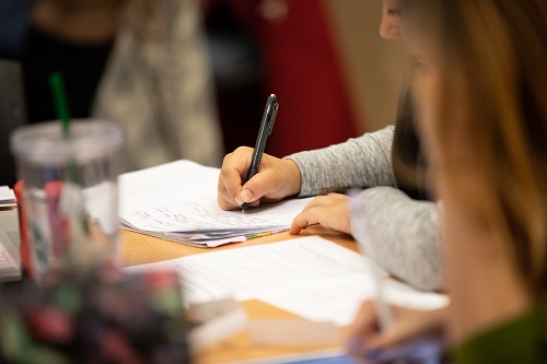 Student writing at desk during class.