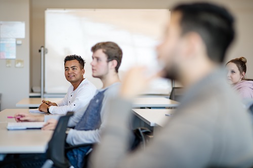 Four students in a classroom listening to a lecture.