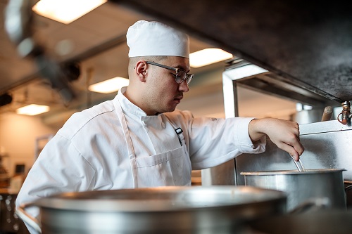 Student in HLC kitchen stirring a pot.