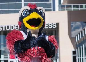 Rowdy giving thumbs up and standing in front of Student Success Building.