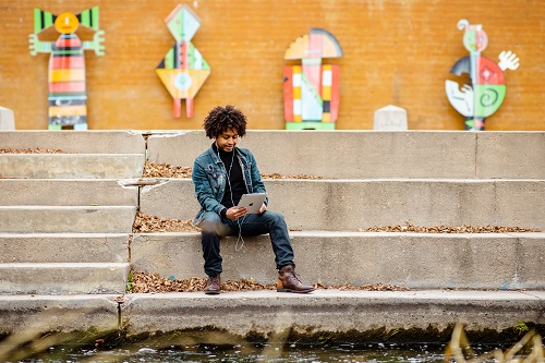 Student Agazi Abay studying on tablet along Cherry Creek bike path.