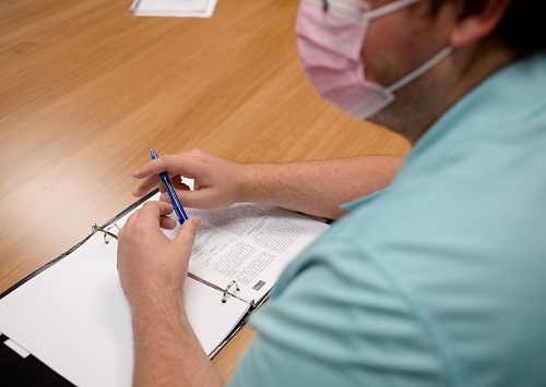 Over-the-shoulder shot of a masked student taking notes in class.