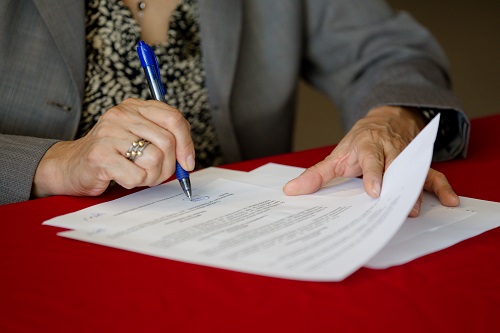 Close up of a woman signing a set of documents.